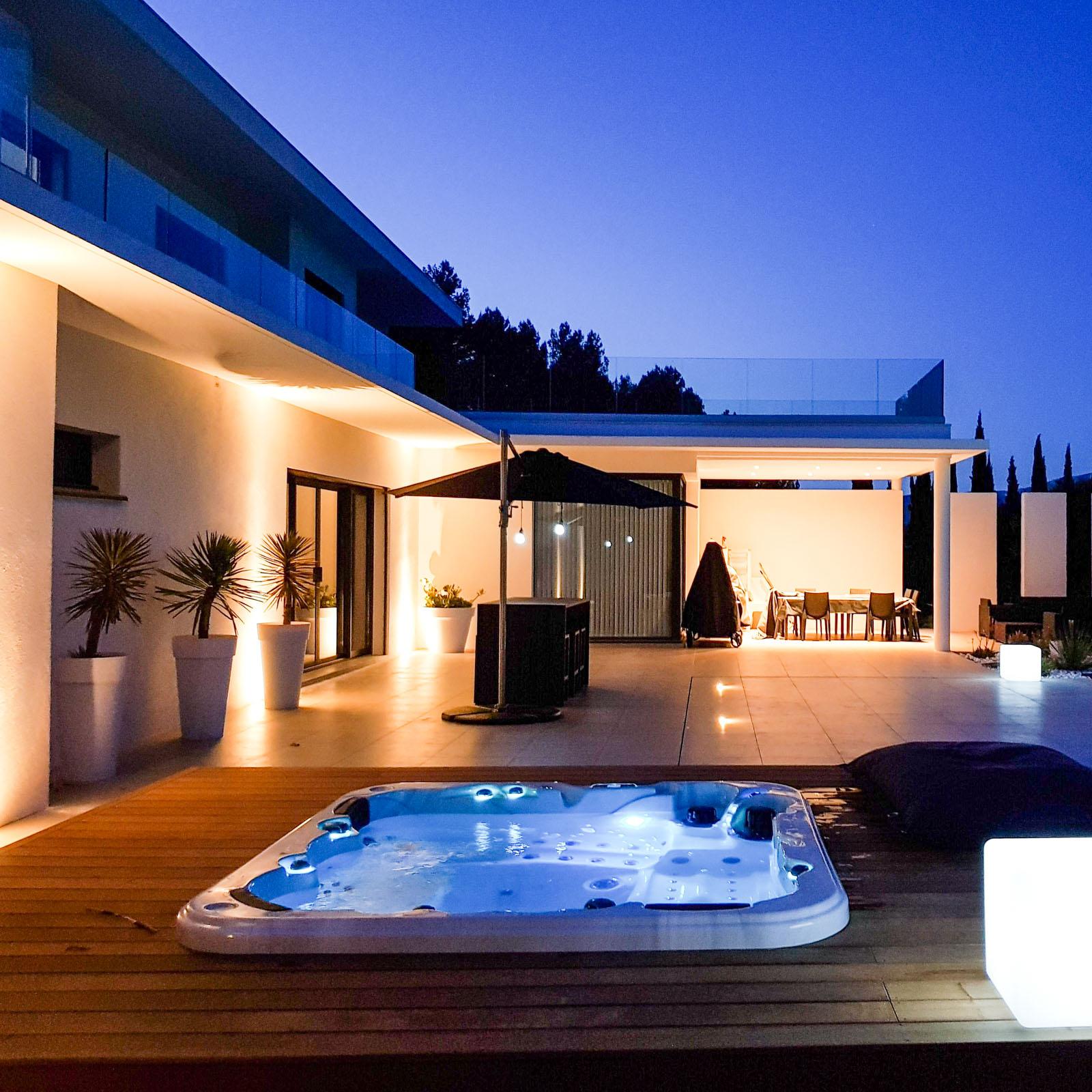 Spa encastré illuminé de nuit avec éclairage LED bleu dans une villa contemporaine
